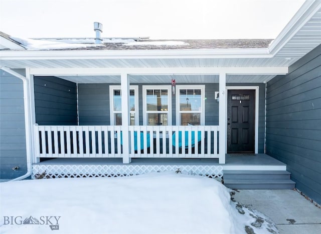 snow covered property entrance featuring a porch