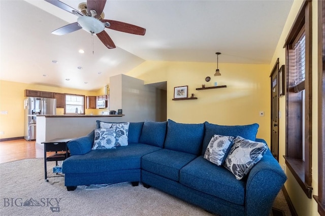 living area featuring a ceiling fan, lofted ceiling, and baseboards