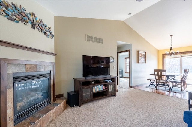 living area with visible vents, a chandelier, a tiled fireplace, carpet flooring, and high vaulted ceiling