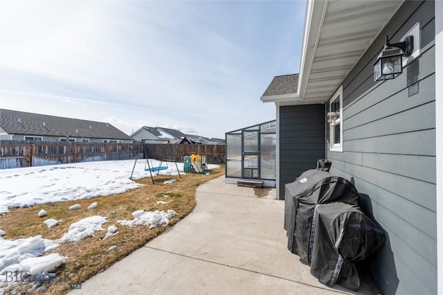 snow covered patio with a fenced backyard and a residential view