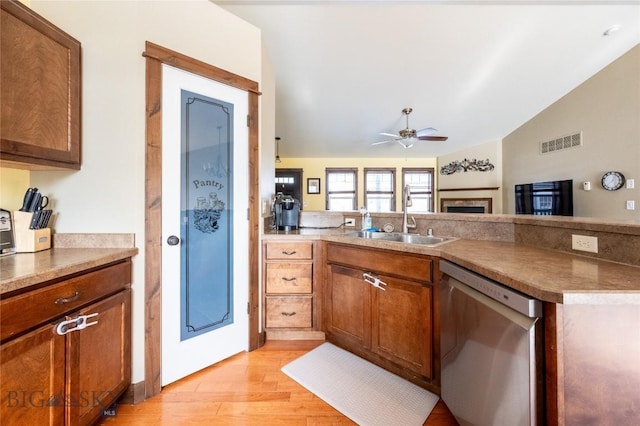 kitchen with a peninsula, a sink, visible vents, brown cabinets, and dishwasher