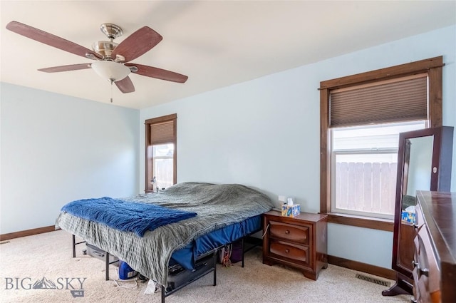 bedroom with a ceiling fan, light colored carpet, multiple windows, and baseboards