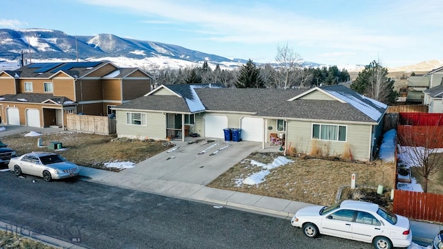 ranch-style home with concrete driveway, a mountain view, an attached garage, and fence