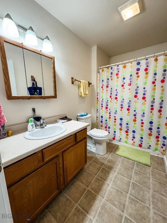 bathroom featuring toilet, a shower with shower curtain, and vanity