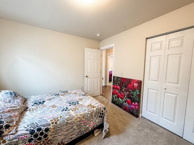 bedroom featuring a closet, light carpet, and a textured ceiling