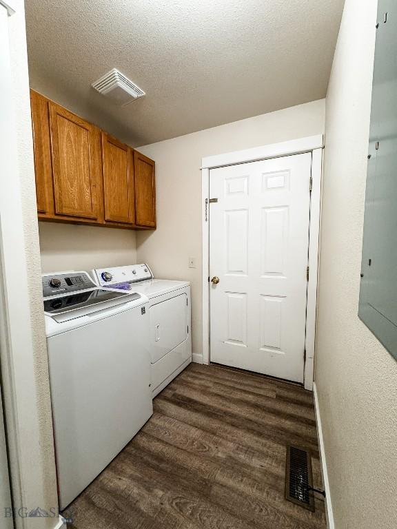 washroom featuring dark wood finished floors, cabinet space, washing machine and dryer, and visible vents