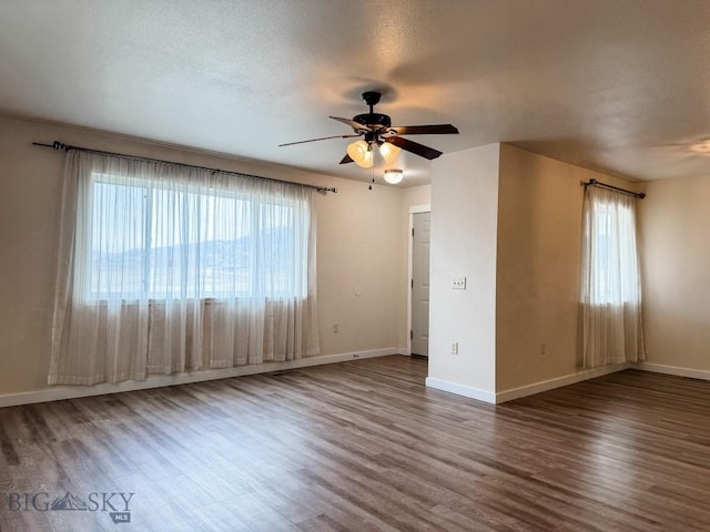 spare room with baseboards, a ceiling fan, wood finished floors, and a textured ceiling