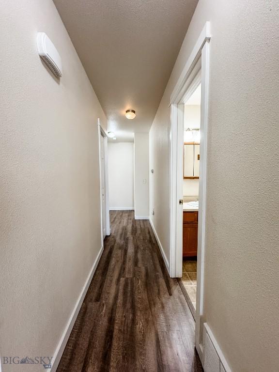 hallway with baseboards and dark wood-style floors