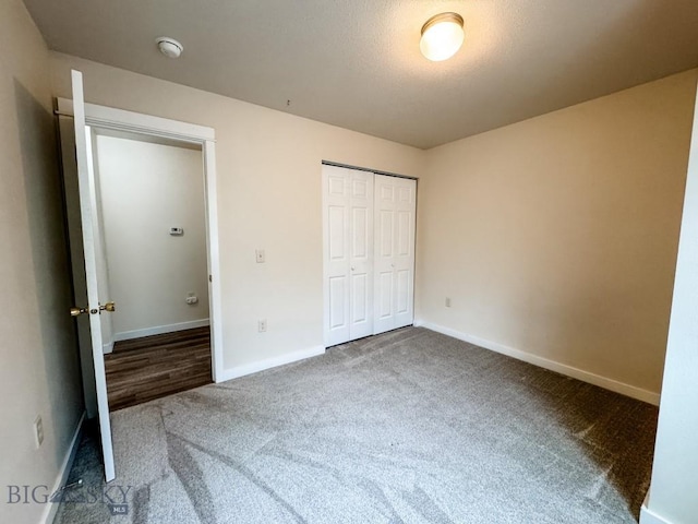 unfurnished bedroom with carpet floors, a closet, and baseboards
