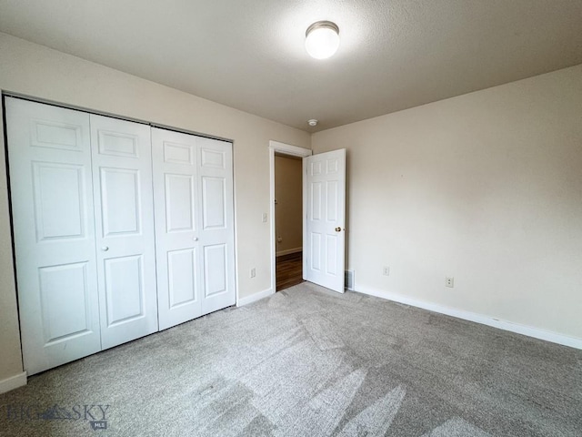 unfurnished bedroom featuring baseboards, carpet flooring, and a closet