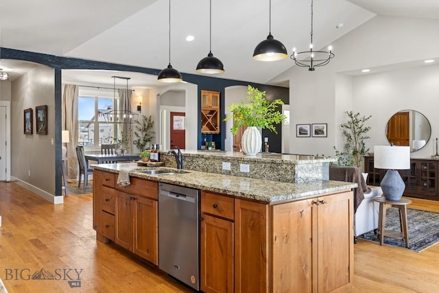 kitchen with arched walkways, light stone counters, a sink, stainless steel dishwasher, and light wood-type flooring