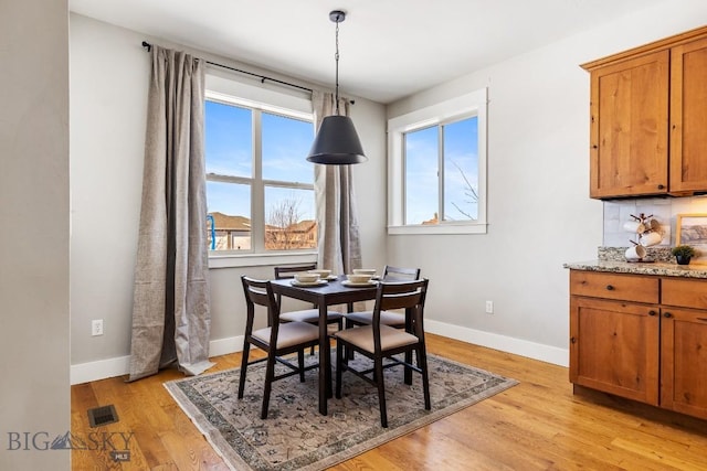 dining area featuring baseboards, light wood-style floors, visible vents, and a healthy amount of sunlight