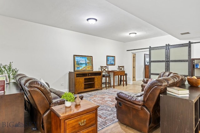 living room featuring a barn door, visible vents, and baseboards