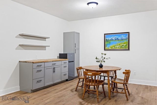 dining space with light wood-style flooring and baseboards