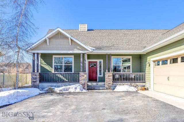 craftsman-style house featuring a porch, an attached garage, driveway, roof with shingles, and a chimney