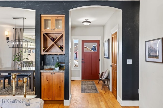 interior space with arched walkways, a notable chandelier, and light wood-style floors