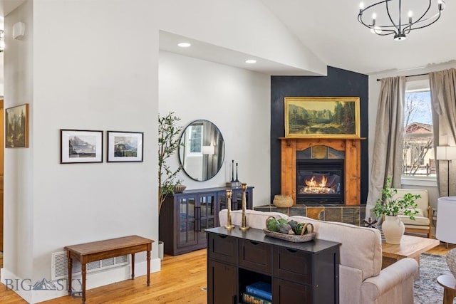 living room featuring a tiled fireplace, lofted ceiling, an inviting chandelier, light wood-type flooring, and recessed lighting