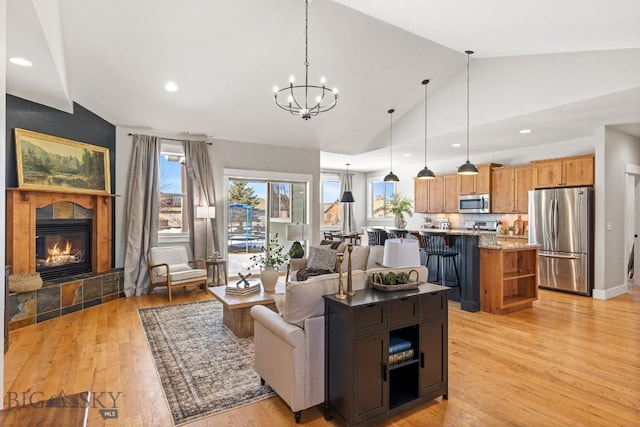 living room featuring recessed lighting, baseboards, light wood finished floors, a tiled fireplace, and an inviting chandelier