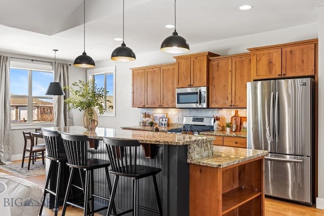 kitchen featuring light stone counters, stainless steel appliances, backsplash, brown cabinets, and open shelves