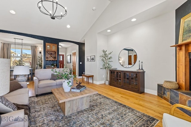 living room featuring arched walkways, a notable chandelier, baseboards, and wood finished floors