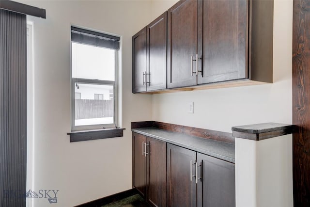 kitchen featuring dark countertops, dark brown cabinetry, and baseboards