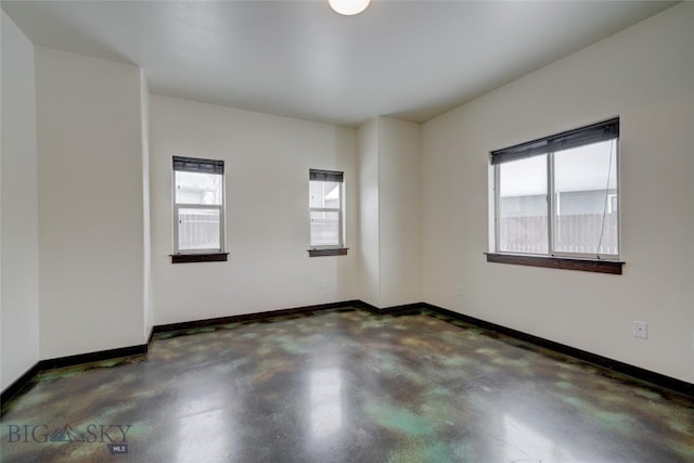 unfurnished room with baseboards, plenty of natural light, and finished concrete floors