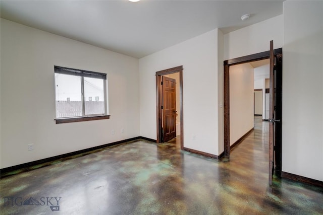 unfurnished room featuring concrete floors and baseboards