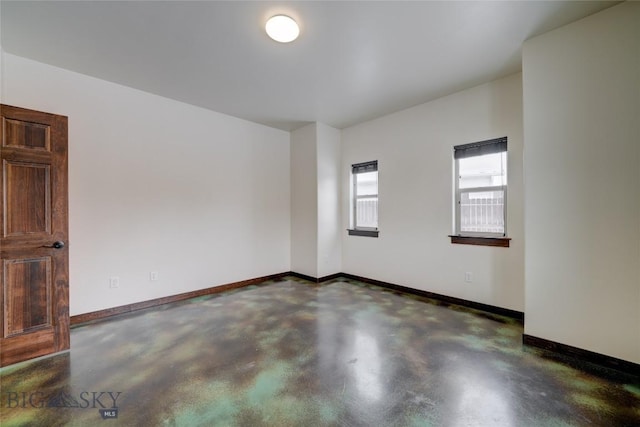 unfurnished room featuring finished concrete flooring and baseboards