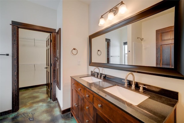 bathroom with double vanity, baseboards, concrete flooring, and a sink