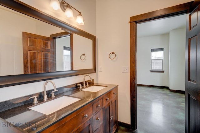 bathroom with finished concrete flooring, a sink, and baseboards