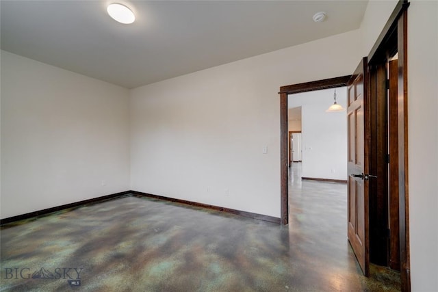 empty room with concrete flooring and baseboards