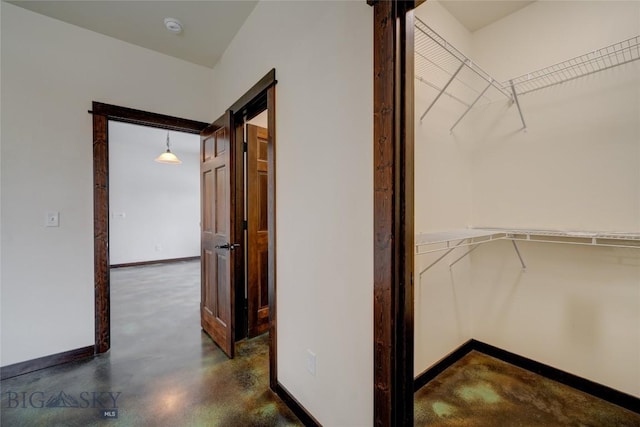 hall featuring concrete floors and baseboards