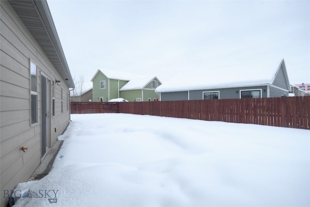 snowy yard with a fenced backyard