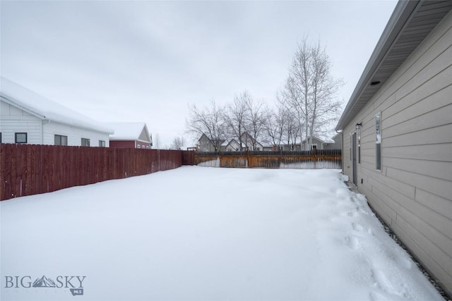 yard covered in snow with a fenced backyard