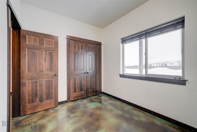 unfurnished bedroom featuring a closet, finished concrete floors, and baseboards