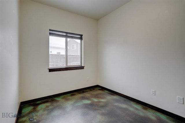 unfurnished room with concrete floors and baseboards