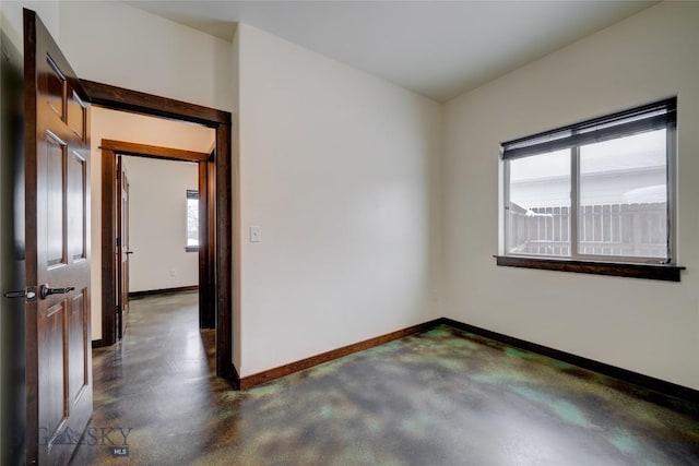 unfurnished room featuring baseboards and concrete flooring