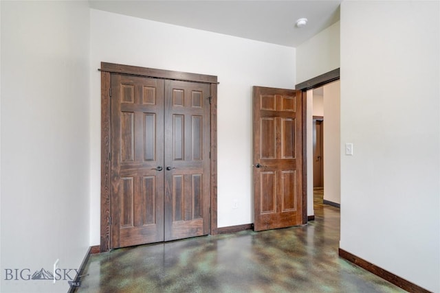 unfurnished bedroom featuring concrete flooring, baseboards, and a barn door