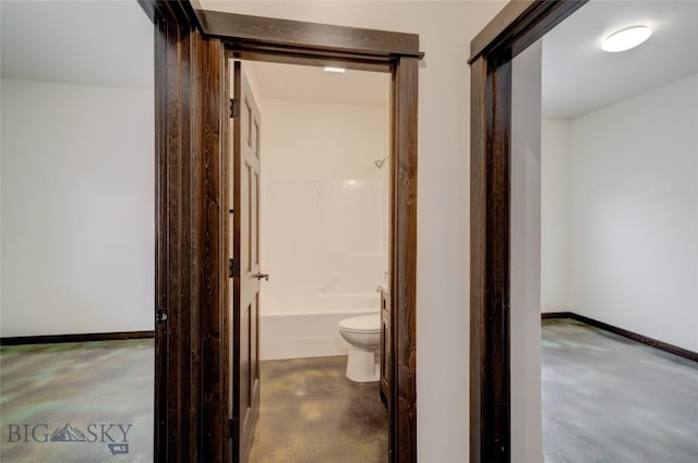 hallway featuring finished concrete flooring and baseboards