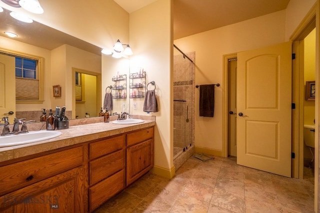 full bathroom featuring a stall shower, a sink, baseboards, and double vanity