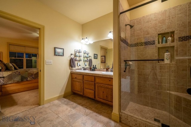 bathroom featuring double vanity, connected bathroom, a sink, and tiled shower