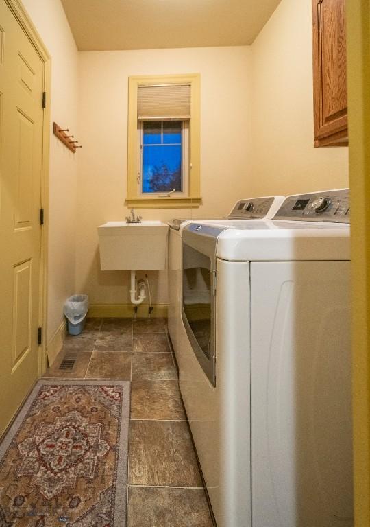 laundry area featuring cabinet space, baseboards, a sink, and independent washer and dryer