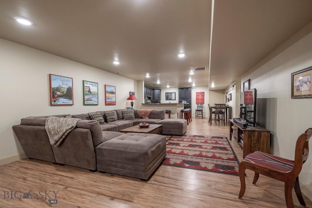 living room featuring light wood-type flooring, visible vents, and recessed lighting