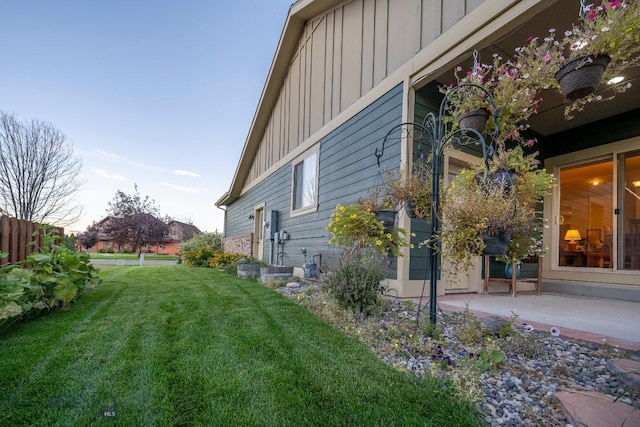 view of side of property featuring a patio, board and batten siding, and a lawn