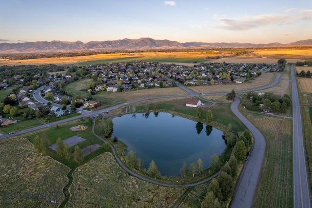 aerial view at dusk featuring a water and mountain view