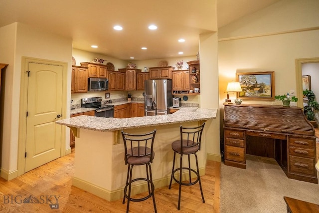 kitchen with recessed lighting, appliances with stainless steel finishes, light stone countertops, a peninsula, and a kitchen bar