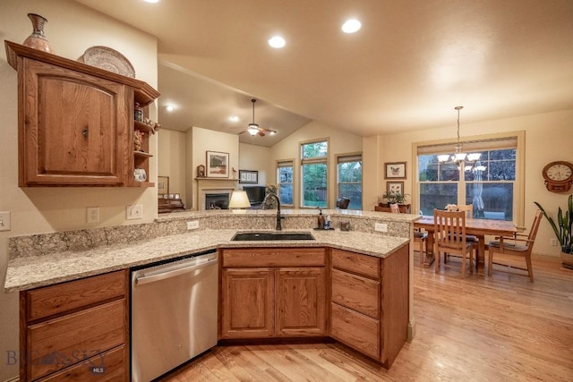 kitchen with a fireplace, lofted ceiling, stainless steel dishwasher, a sink, and a peninsula