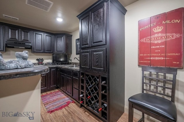 kitchen with dark countertops, light wood-style floors, visible vents, and a sink