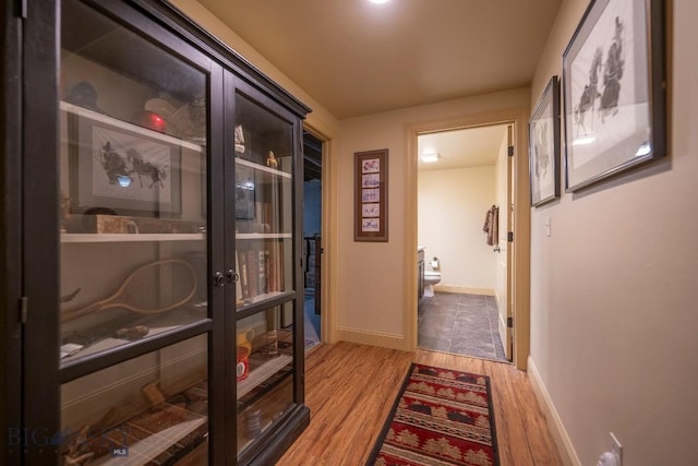 hallway featuring light wood-style flooring and baseboards