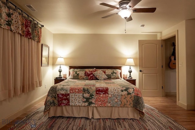 bedroom featuring ceiling fan, wood finished floors, visible vents, and baseboards